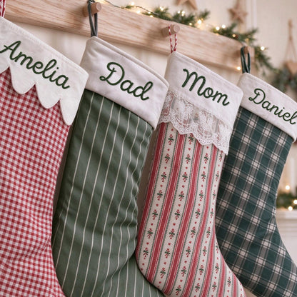 May include: Four Christmas stockings hanging in a row, each featuring a white cuff embroidered with the names Amelia, Dad, Mom, and Daniel in green thread. The stockings display various patterns including red gingham, green pinstripe, red striped floral, and green plaid.