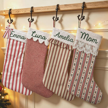 May include: Four Christmas stockings hanging from black metal hooks. The first is red and white striped with a bow and the name Emma. The second is red and white gingham with the name Luna. The third is striped with a ruffle and the name Amelia. The fourth is floral with lace and the name Mom.